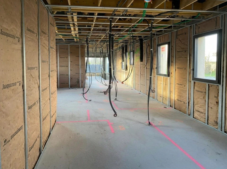 Plombier installant un robinet mural en cuivre rosé dans une salle de bain moderne blanche