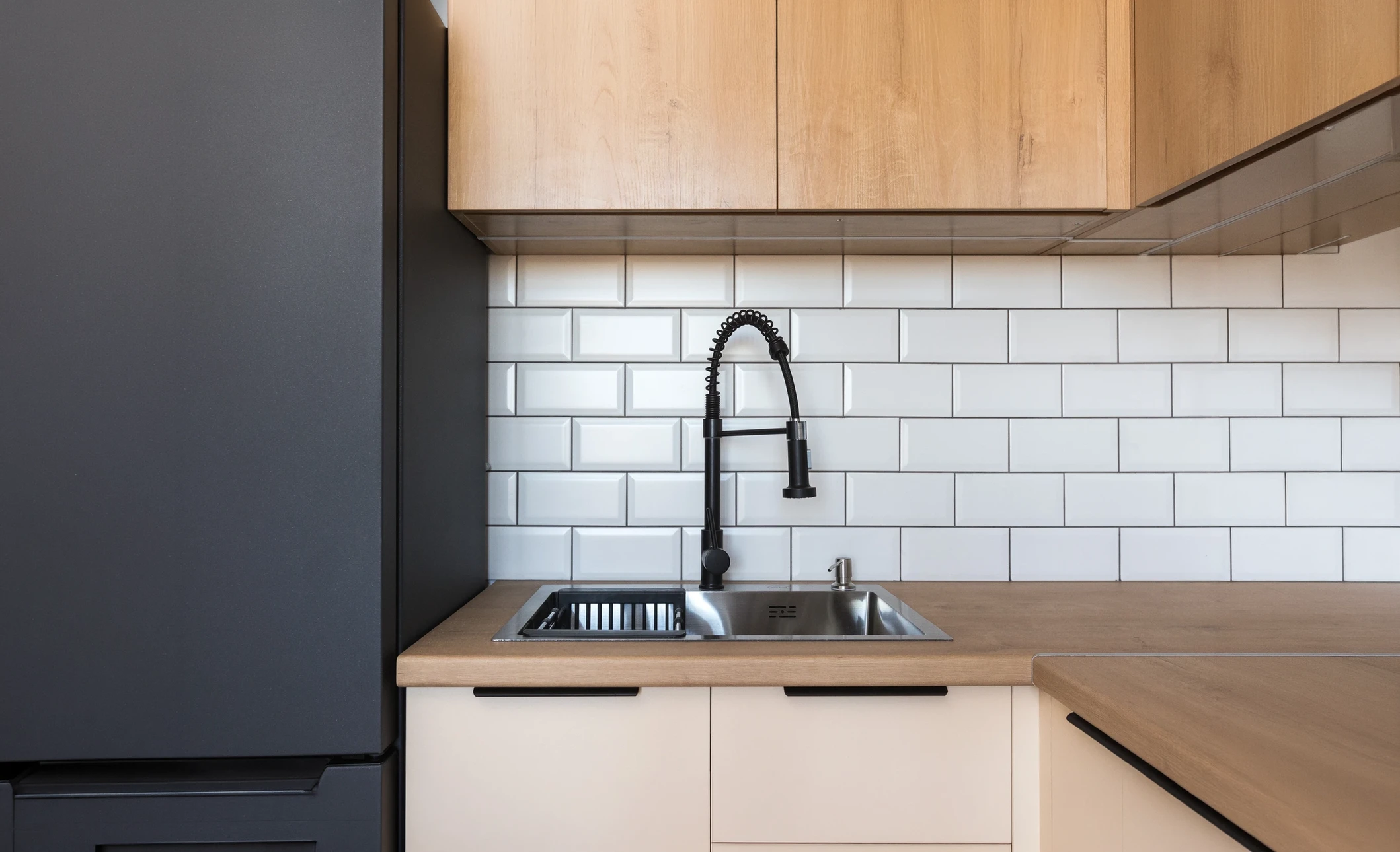 Intérieur cuisine moderne avec plombier en chemise bleue portant ceinture à outils orange