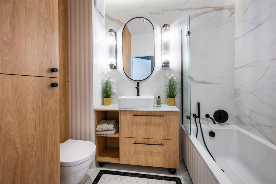 Intérieur de salle de bain en rénovation avec ouvrier appliquant du joint sur carrelage mosaïque