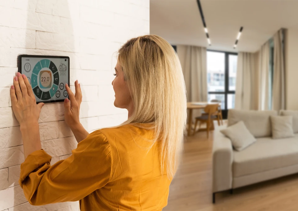 Intérieur résidentiel avec personne utilisant smartphone pour contrôler thermostat intelligent mural